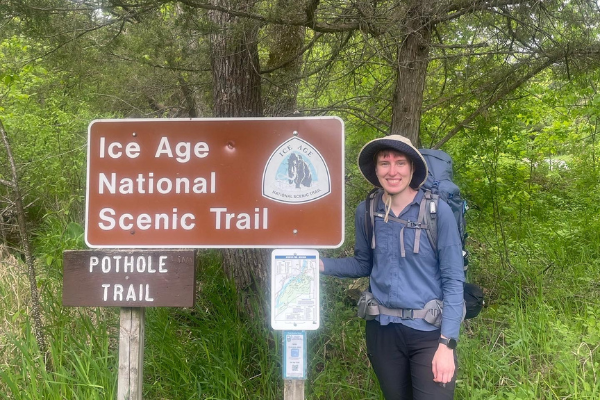 Bryn Langrehr posing next to a sign for the Pothole Trail at the start of her thru-hike in St. Croix Falls, WI. Photo by Bryn Langrehr.
