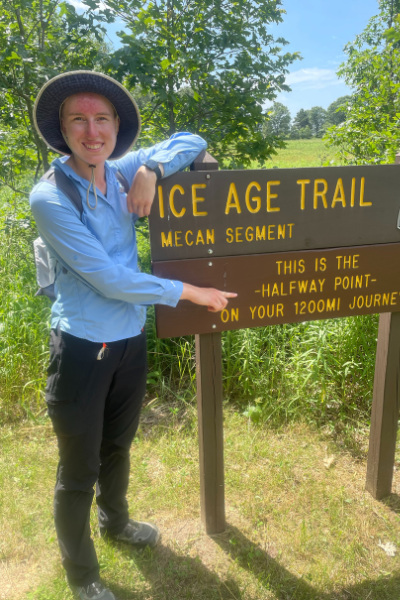 Langrehr standing next to the sign at the Mecan Segment marking the halfway point of the Ice Age Trail. Photo by Bryn Langrehr.