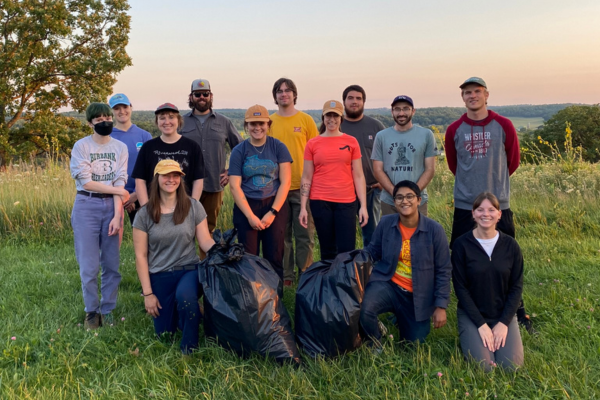 A group of young adults show off the pile of invasive species they collected during and stewardship event.