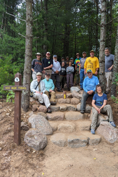 A group of volunteers pose for a picture on a new constructed stone staircase.