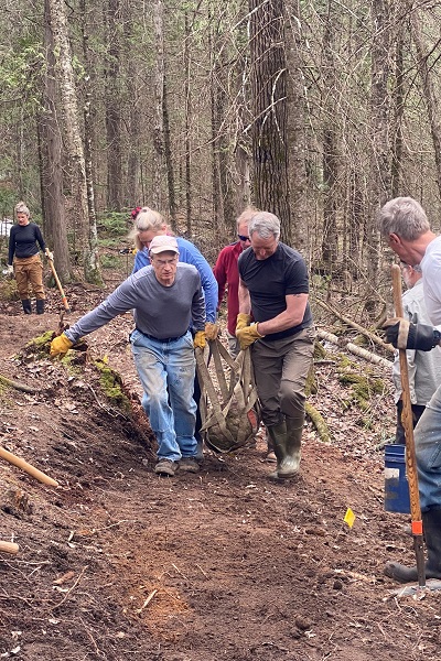 Volunteers work together to haul stone for a stone water crossing.