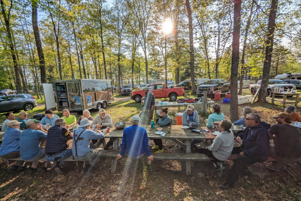 A group of volunteers sit around a picnic table and enjoy a meal together.