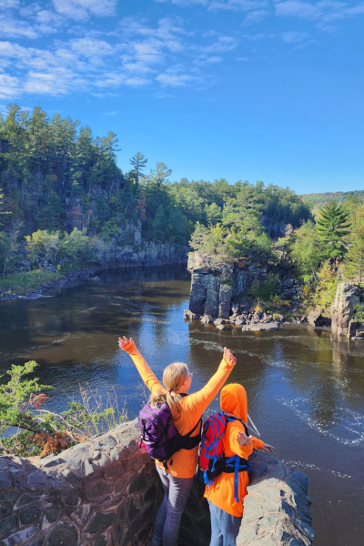 Two young hikers in blaze orange enjoy a scenic overlook of the St. Croix River.