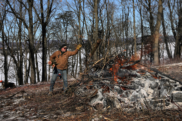 A volunteer throws brush into a fire.