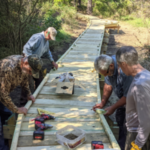 Volunteers carefully measuring out pieces for the edge of the boardwalk. Photo by Dave Caliebe.